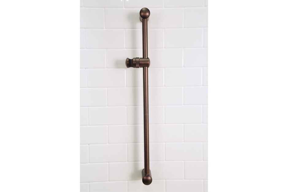 Bronze shower slide bar, mounted vertically, against white subway tile.