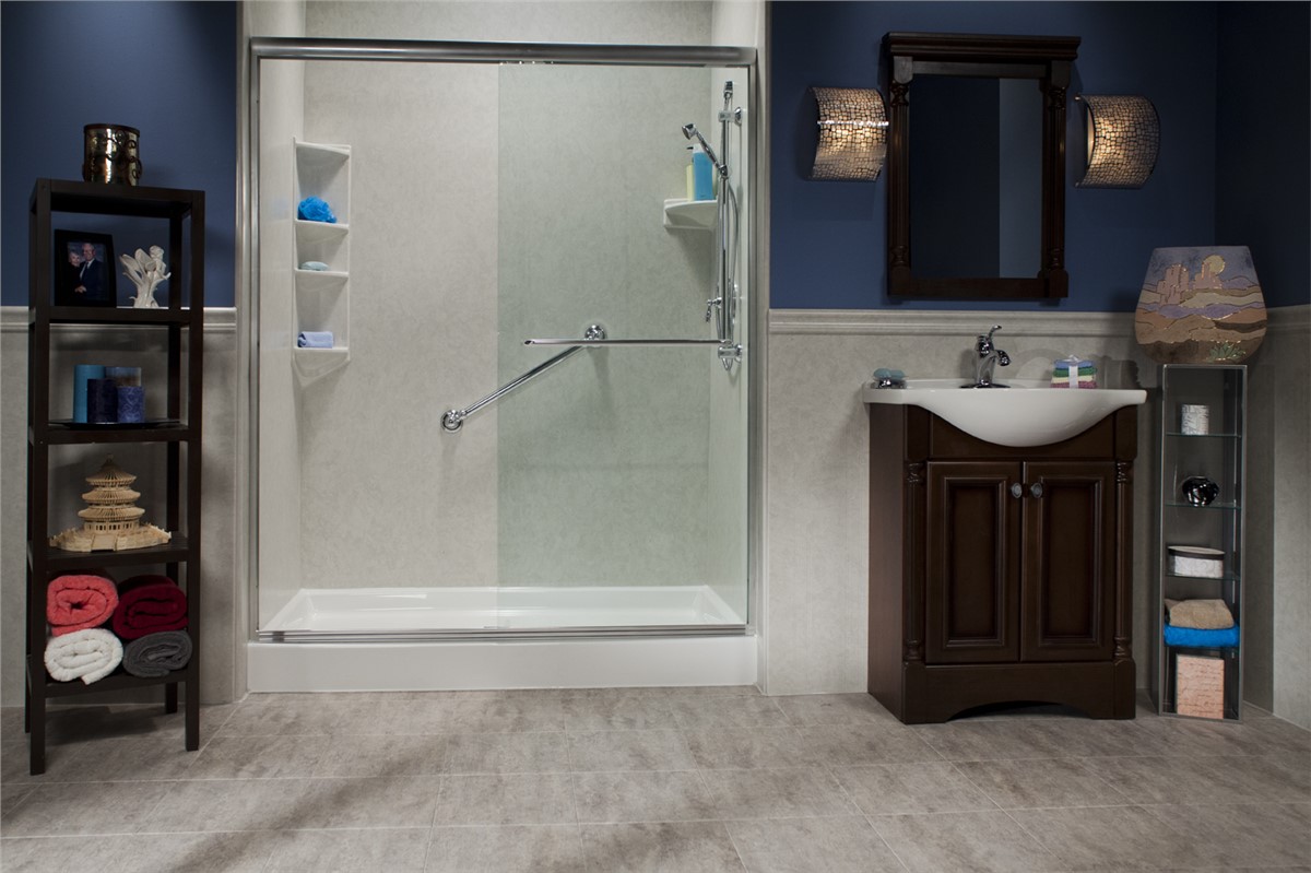 A modern bathroom with a glass shower enclosure, a brown vanity with sink and mirror, open shelving with towels and decor, and a tile floor. The walls are partly blue and partly light-colored paneling.