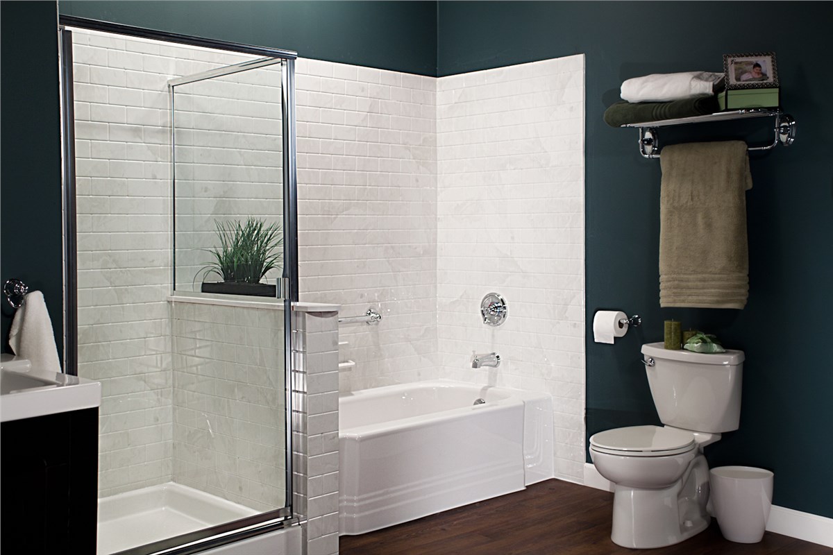 Bathroom with a glass shower door adjacent to a bathtub, white subway tile walls, dark green accent wall, and an elongated toilet.