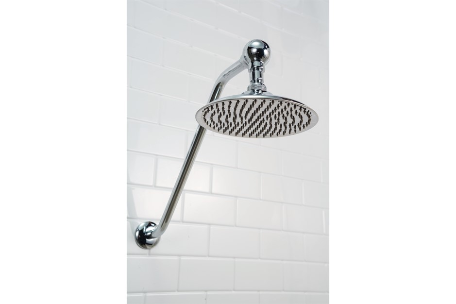 Chrome shower head mounted on white subway tile.