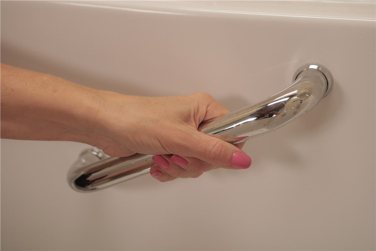 Hand gripping a chrome grab bar mounted on a white wall.