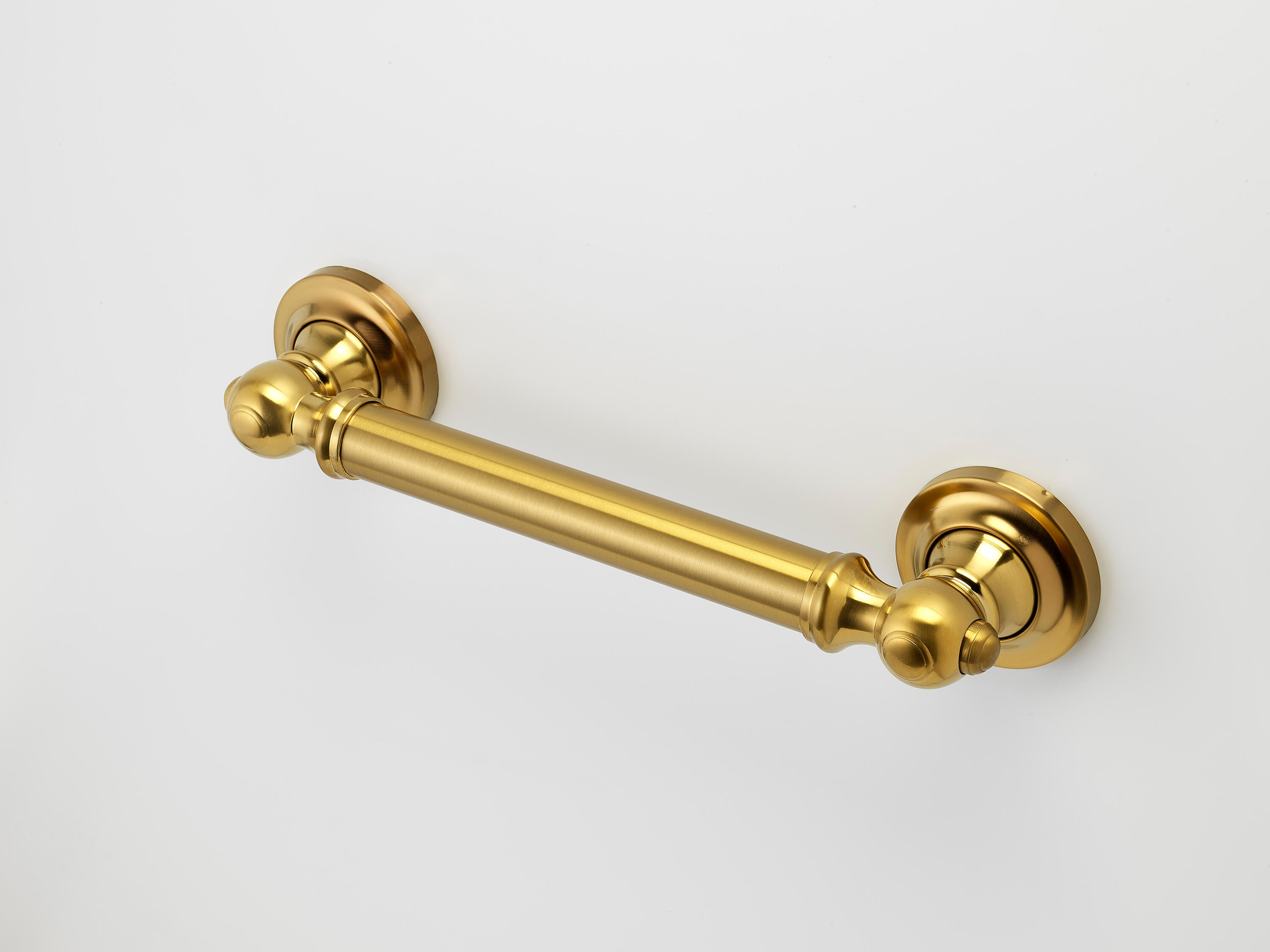 A horizontal gold metal grab bar with decorative round wall mounts, installed against a plain white background.