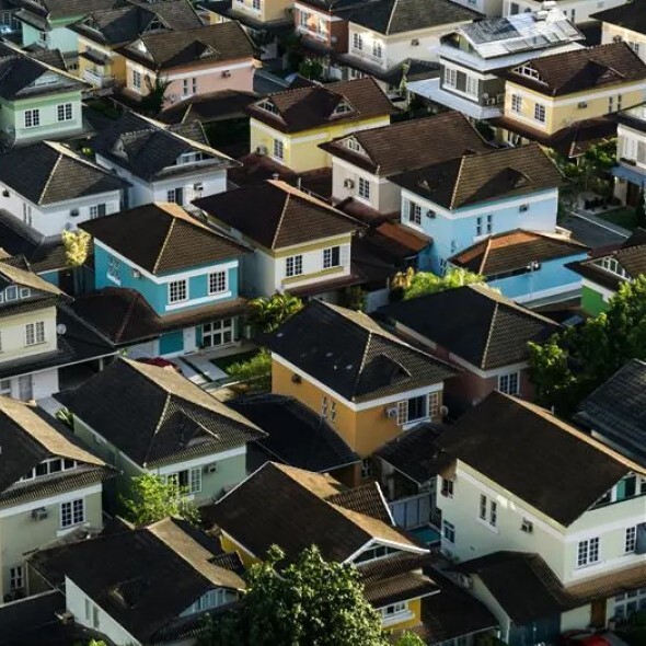 Aerial view of closely packed, single-family homes in a residential neighborhood, featuring various pastel exterior paint colors.