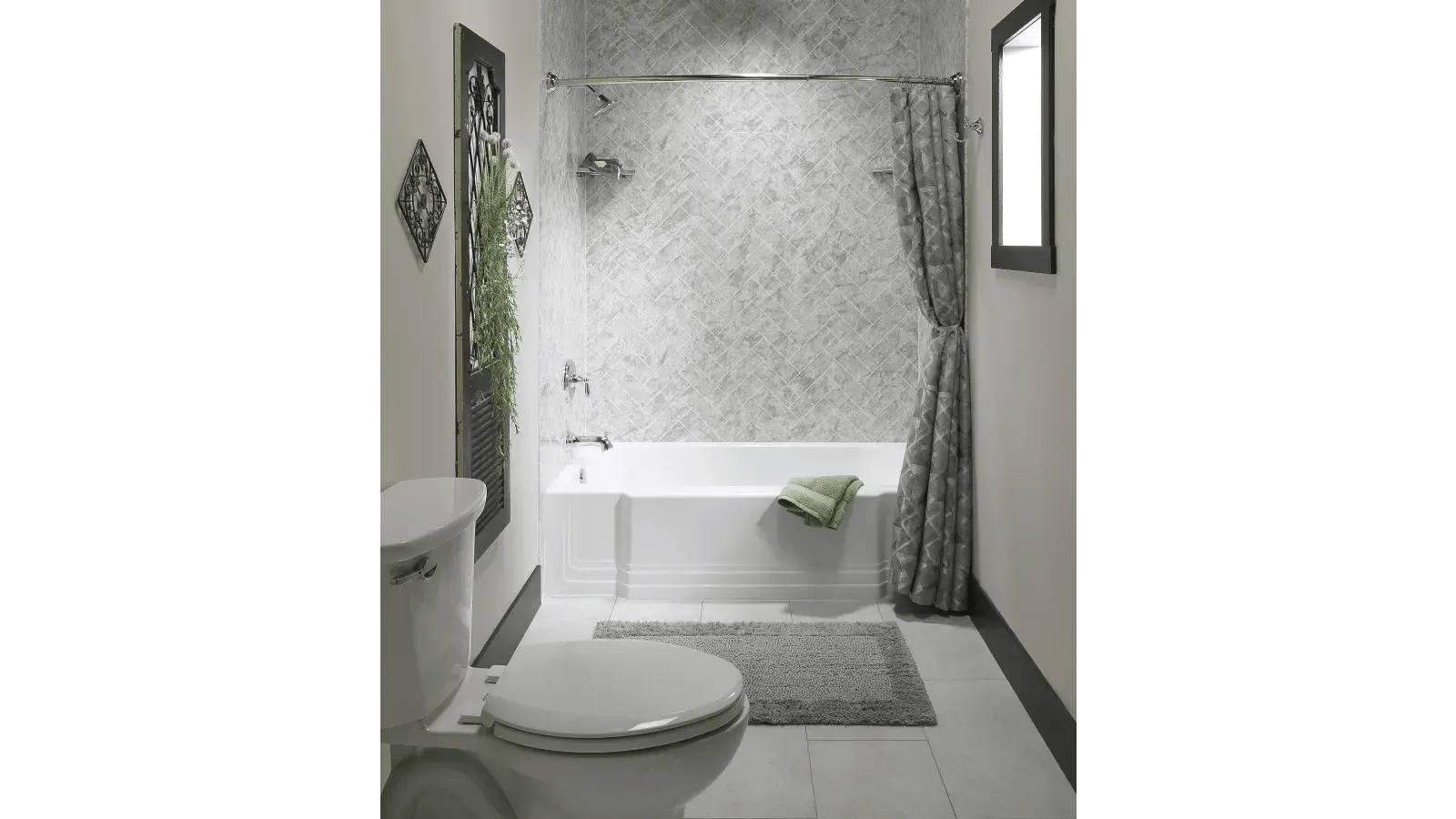 Bathroom featuring a white toilet, white bathtub with shower, textured grey shower curtain and backsplash, grey floor mat and home decorations including a black framed, shuttered door and geometrically shaped wall decor.