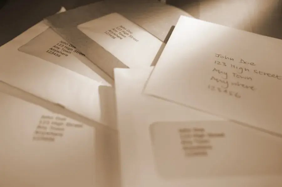 Several envelopes addressed to John Doe, 123 High Street, Any Town, Anywhere, 123456.