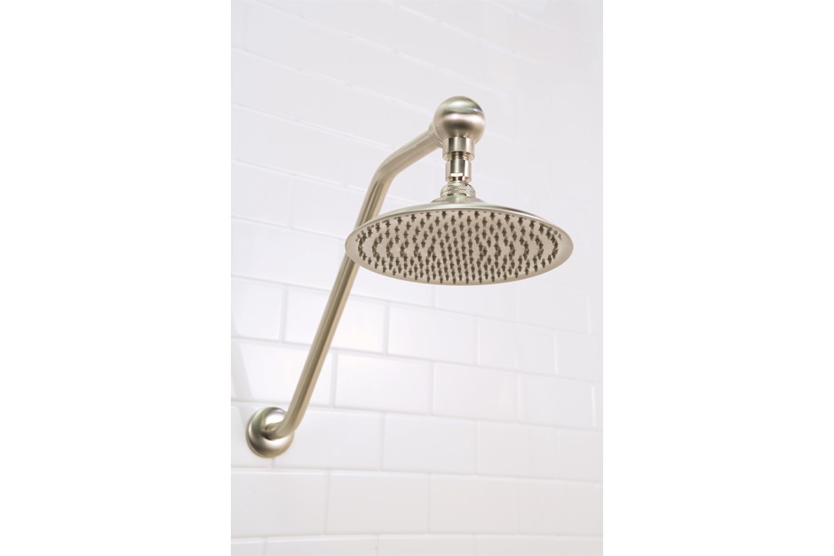 Brushed nickel rain shower head attached to a white tiled wall.