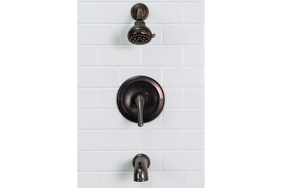 Dark Bronze shower fixtures including a shower head, shower control, and spout installed on a white-tiled wall.