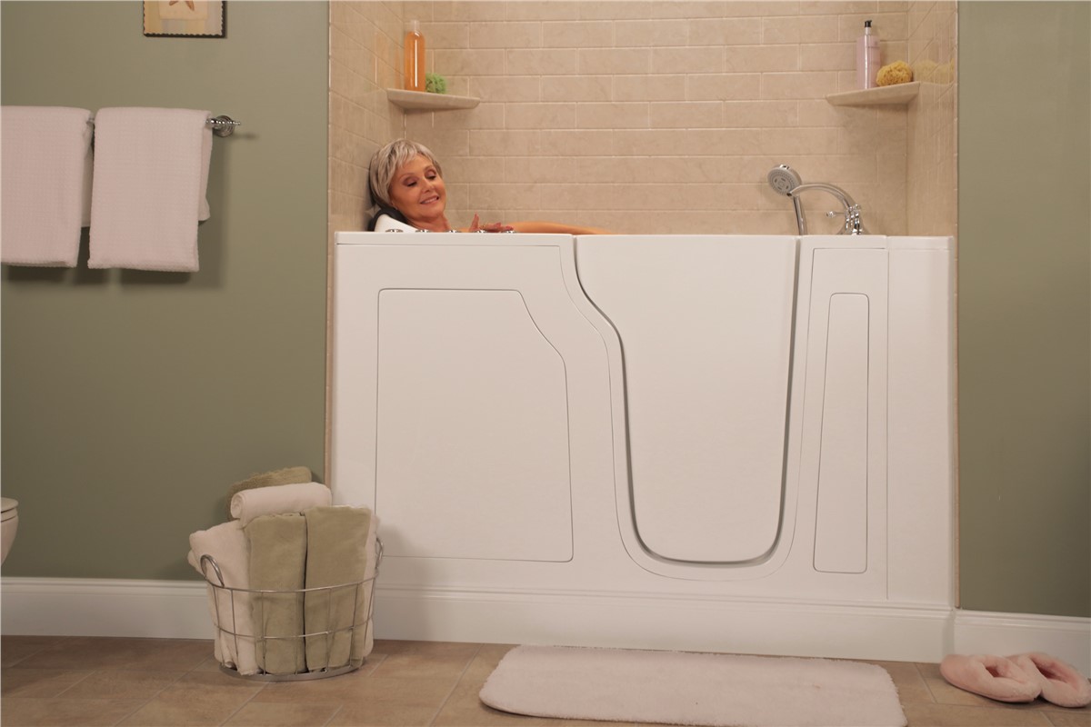 Older woman relaxes in a white walk-in bathtub, smiling contentedly.