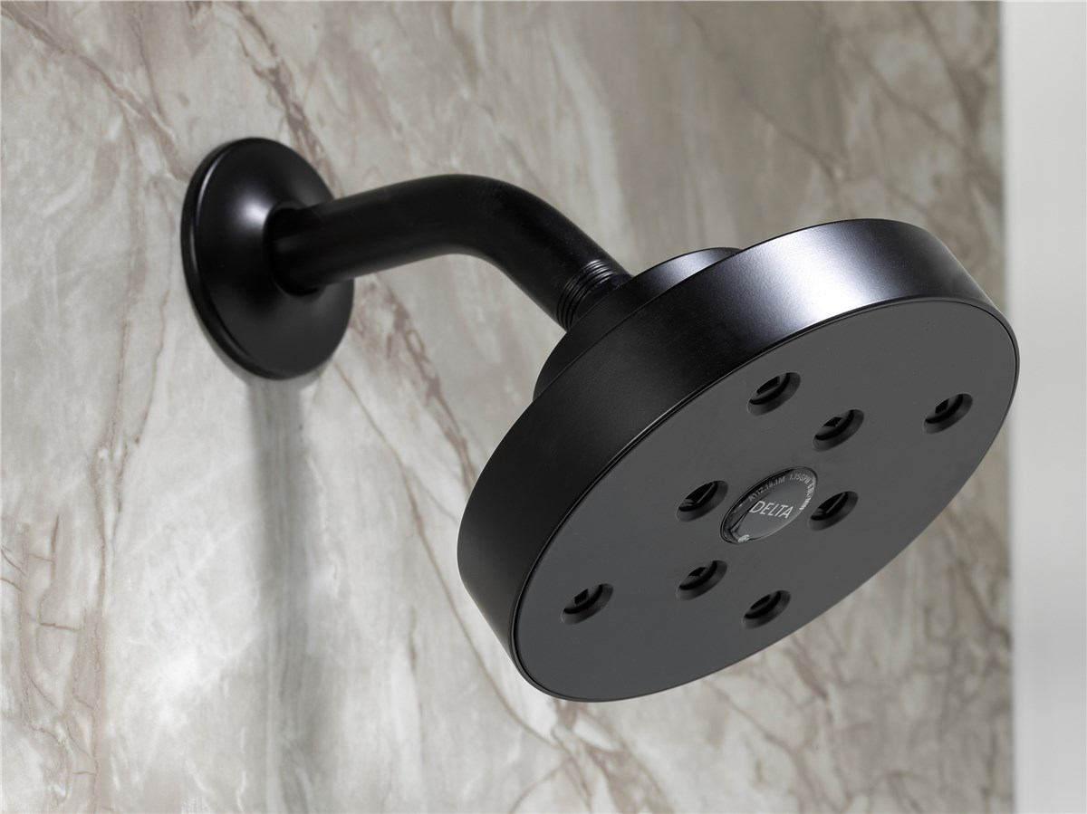 Close-up of a sleek black showerhead mounted on a marble wall, featuring multiple spray nozzles and a subtle Delta logo in the center.